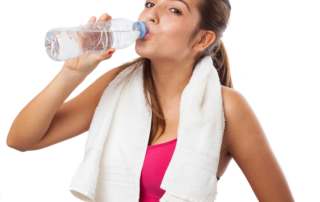 foto de uma jovem mulher bebendo água durante atividade física