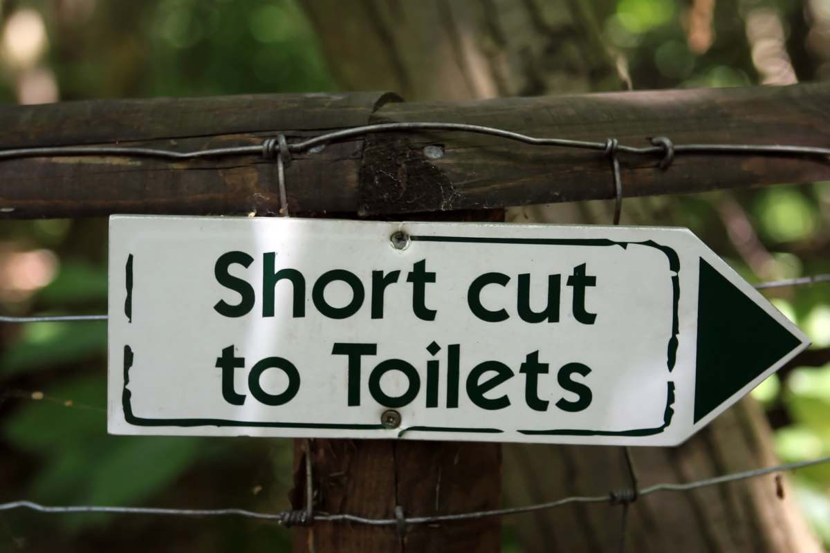 placa informativa indicando o banheiro para falar de incontinência urinária